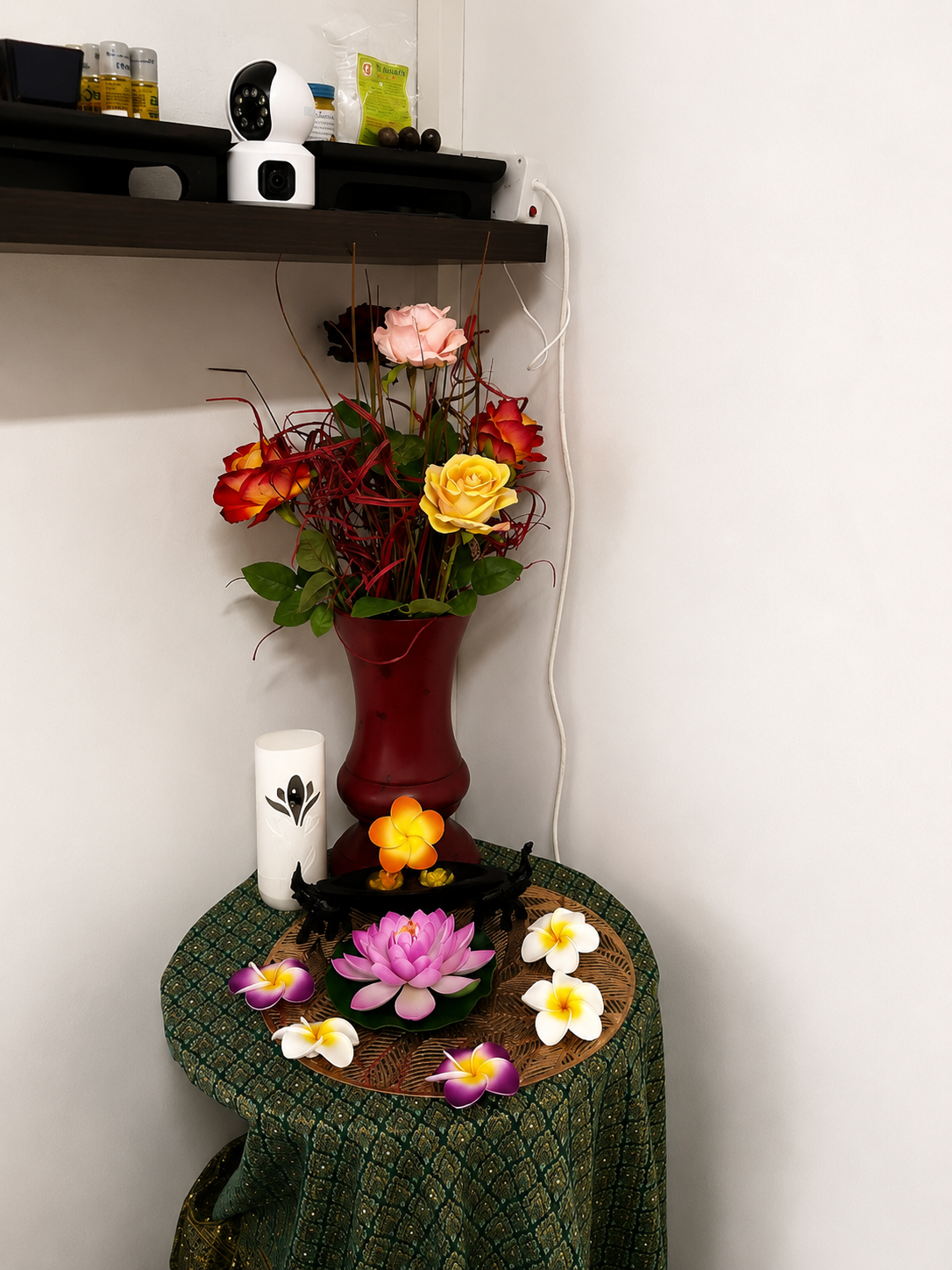 Lotus and frangipani corner Thai silk draped table with a pink lotus, frangipani blooms, candle and floral vase in the treatment room corner
